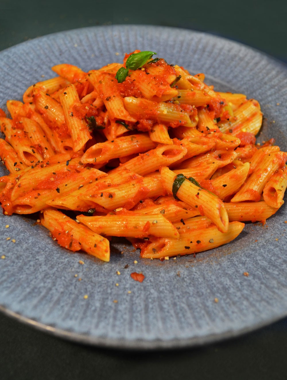 penne all'arrabbiata on a plate with basil garnish